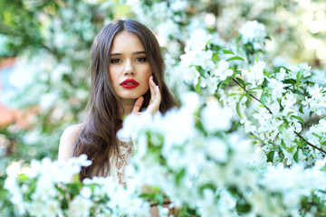 Portrait of young beautiful woman in spring blossom trees.