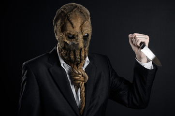 Fear and Halloween theme: a brutal killer in a mask holding a knife on a dark background in the studio - 86512572