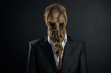Fear and Halloween theme: a brutal killer in a mask on a dark background in the studio