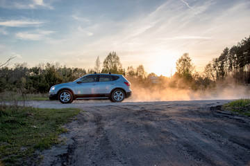 Cloud of dust behid a car driving through a dry unmade road