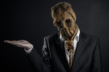 Fear and Halloween theme: a brutal killer in a mask on a dark background in the studio