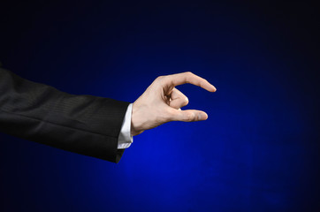 Fototapeta na wymiar Businessman and gesture topic: a man in a black suit and white shirt showing hand gesture on an isolated dark blue background in studio
