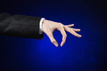 Businessman and gesture topic: a man in a black suit and white shirt showing hand gesture on an isolated dark blue background in studio