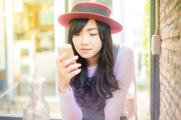 Asian woman using smartphone at coffee shop in the morning