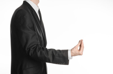 Businessman and gesture topic: a man in a black suit and tie holding his hand in front of him and shows a pinch gesture on an isolated white background in studio