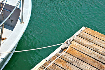 Deatil of boat tied to a woodn dock with nautical rope