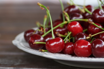 red cherry on the plate standing on wooden background.