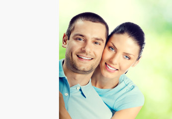 Young lovely couple with blank signboard, outdoor