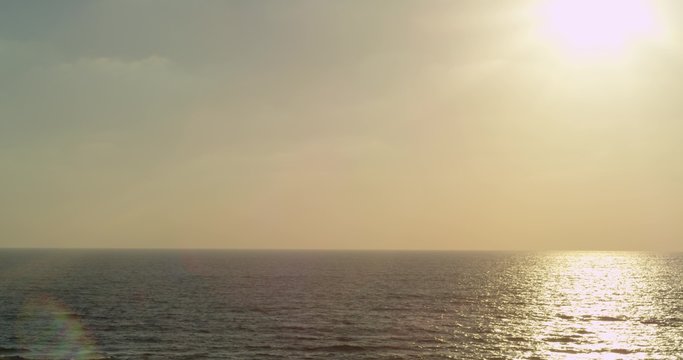 Beautiful Mediterranean sunset, blue waves and yellow-pink sunset. In the sky flying a triangular kite