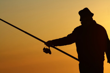 Homem a pescar ao por-do-sol.