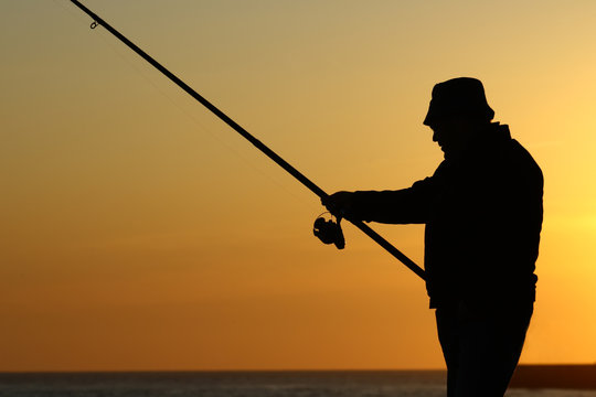 Homem a pescar ao por-do-sol.