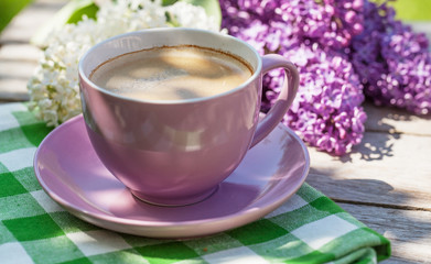 Obraz na płótnie Canvas Coffee cup and colorful lilac flowers