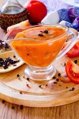 Tomato sauce in a glass gravy boat on a wooden table
