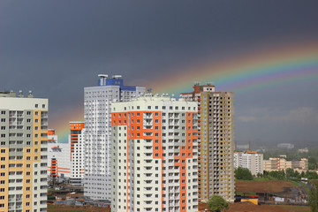 New modern block multistory house on dark sky background in four colors: red, orange, grey and white. Bad weather and rainbow. Building new house