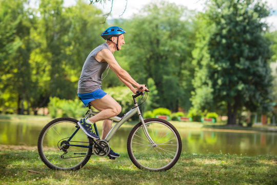 Joyful senior man riding a bike in a park
