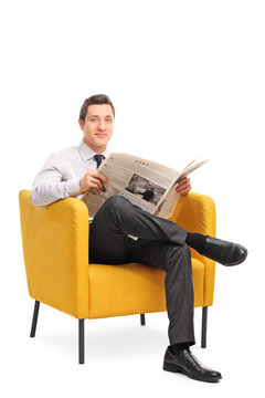 Man sitting in an armchair and holding a newspaper