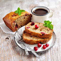 Banana bread loaf with ripe bananas and frozen cranberries on rustic background, selective focus