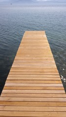 Fototapeta premium A wooden bridge over the sea and the mountains