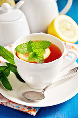 Tea with lemon, mint, and fresh cranberries on  blue background, table setting, selective focus