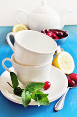 Tea with lemon, mint, and fresh cranberries on  blue background, table setting, selective focus