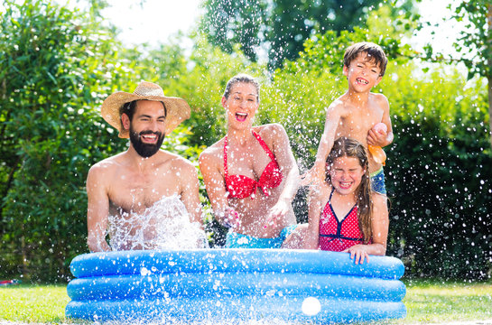 Familie im Garten Pool bei Abkühlung spitzt mit Wasser