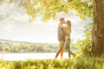 Couple in love on the lake, beneath the trees, kissing