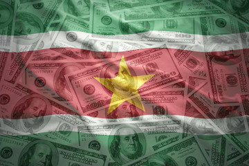 colorful waving surinamese flag on a american dollar money background