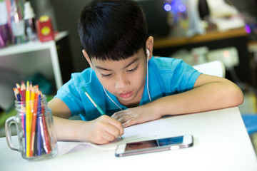 Asian boy using cellphone and painting on a white paper