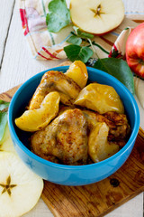 Baked chicken with apples in a bowl on a wooden table