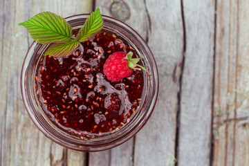 Raspberry jam and fresh raspberry on a rustic wooden table. DOF
