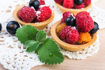  raspberry and bluebery tarts on wooden  table. Fresh fruit cakes
