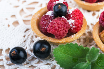  raspberry and bluebery tarts on wooden  table. Fresh fruit cakes