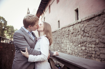 Pretty sunny outdoor portrait of young stylish couple while kiss
