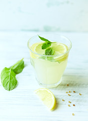 Glass of homemade lemonade with mint and lemon wedges