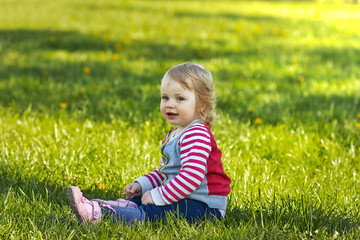 Naklejka na ściany i meble Girl in park sitting on the green grass