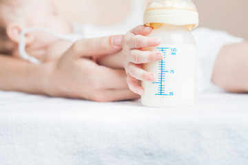 Obraz na płótnie Canvas Baby holding a baby bottle with breast milk