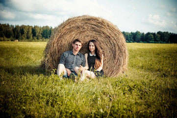 lovers resting in a field near haystacks
