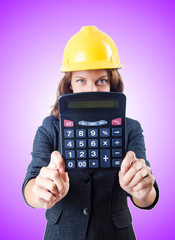 Female builder with calculator against gradient 