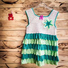 Child dress on hanger on wooden wall background