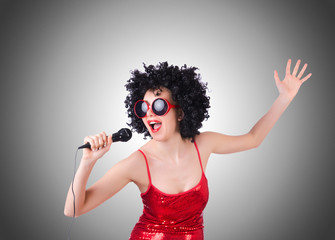 Pop star with mic in red dress against gradient 