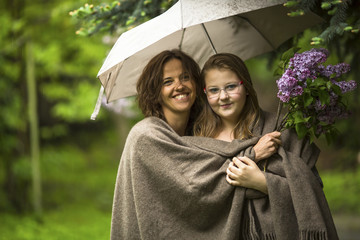 Woman with her daughter under an umbrella in the Park in the rain.