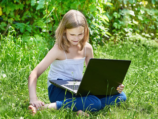 Girl using laptop on grass
