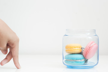 Hand moving towards a jar of macaroons