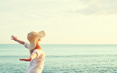 Happy woman in hat is back  opened his hands, enjoys sunset