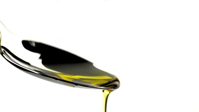 close-up of extra virgin olive oil over a spoon with drops isolated on white background, nutrition concept