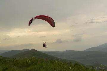 Fototapeten Paraglider tandem flight in mountains at sunset © Edelweiss086