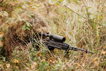 A camouflaged sniper aiming through his scope