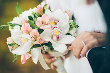 A bride and groom holding a bouquet of white and pink flowers