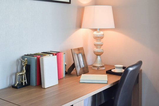 wooden table with reading lamp and books in modern working room
