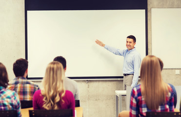 group of students and smiling teacher in classroom